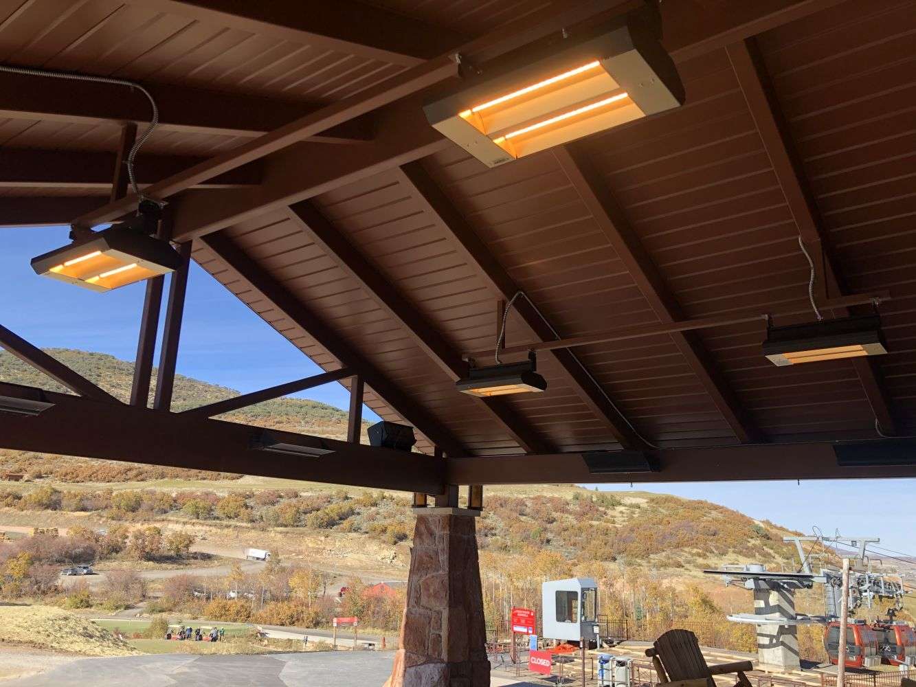 Covered wooden patio with a heater and desert landscape.