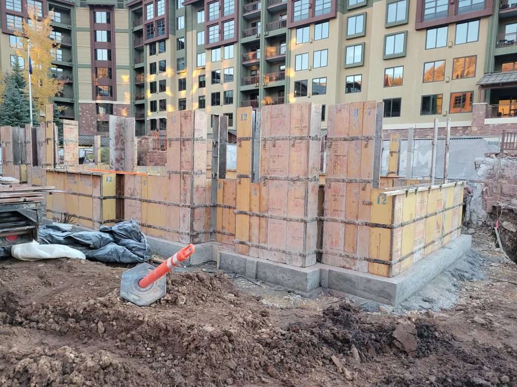 Construction site with wooden framework and scaffolding near a building.