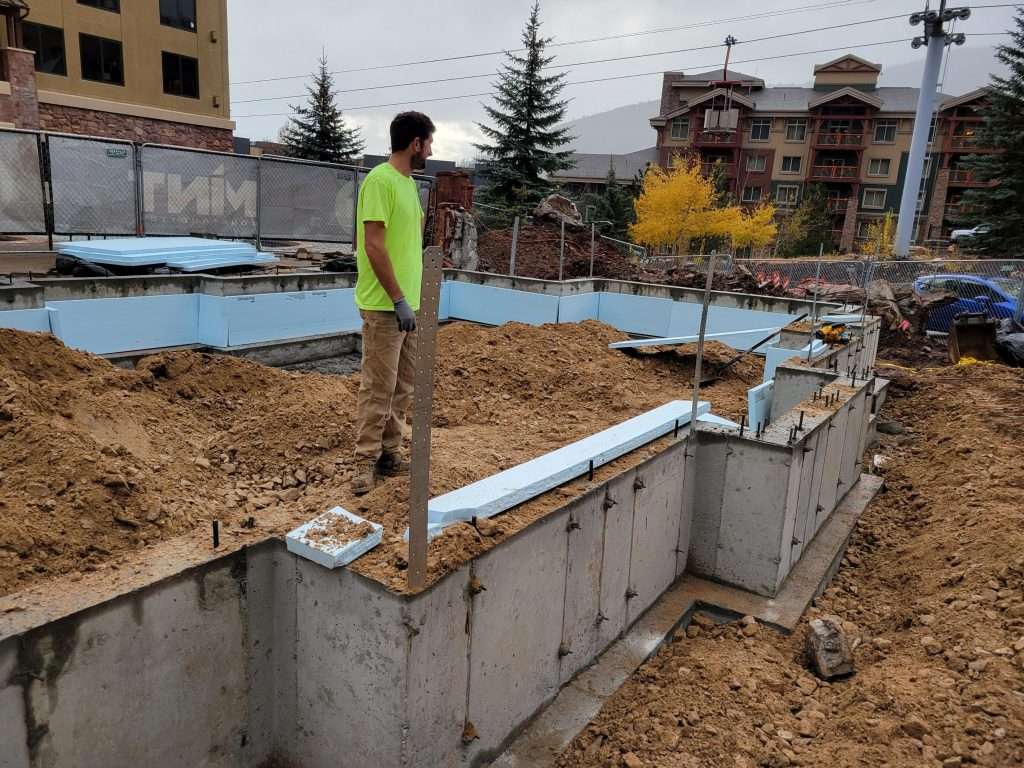 Construction worker standing on foundation walls at a building site.