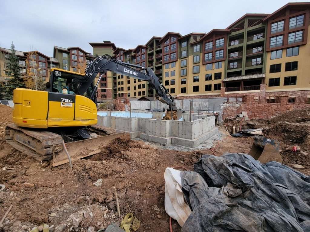 Construction site with excavator and building foundations.