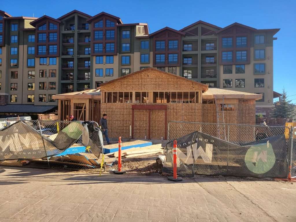 A house under construction with wooden framing and construction materials outside.