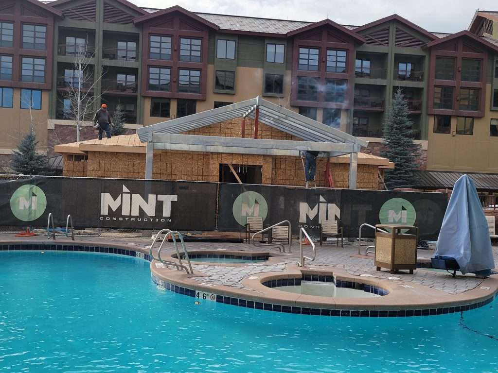 Outdoor pool area with cabanas and Mint-branded umbrellas at a resort.