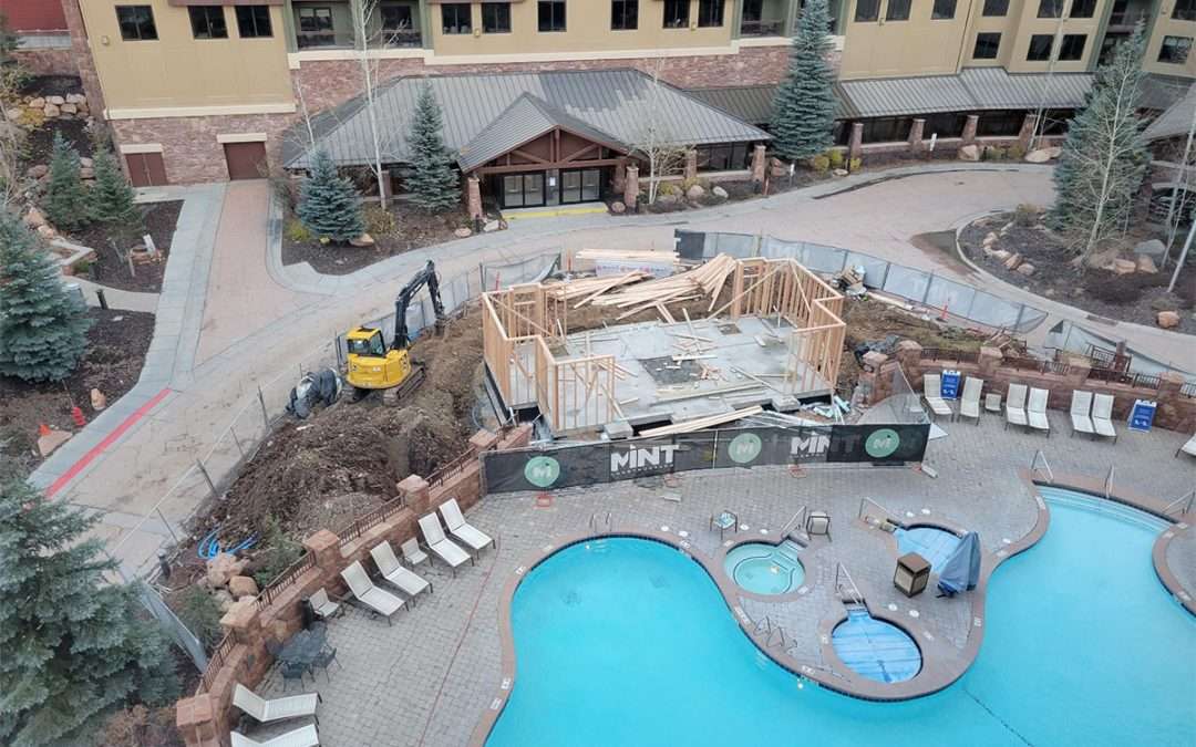 Construction work near a hotel pool area with machinery and building materials.
