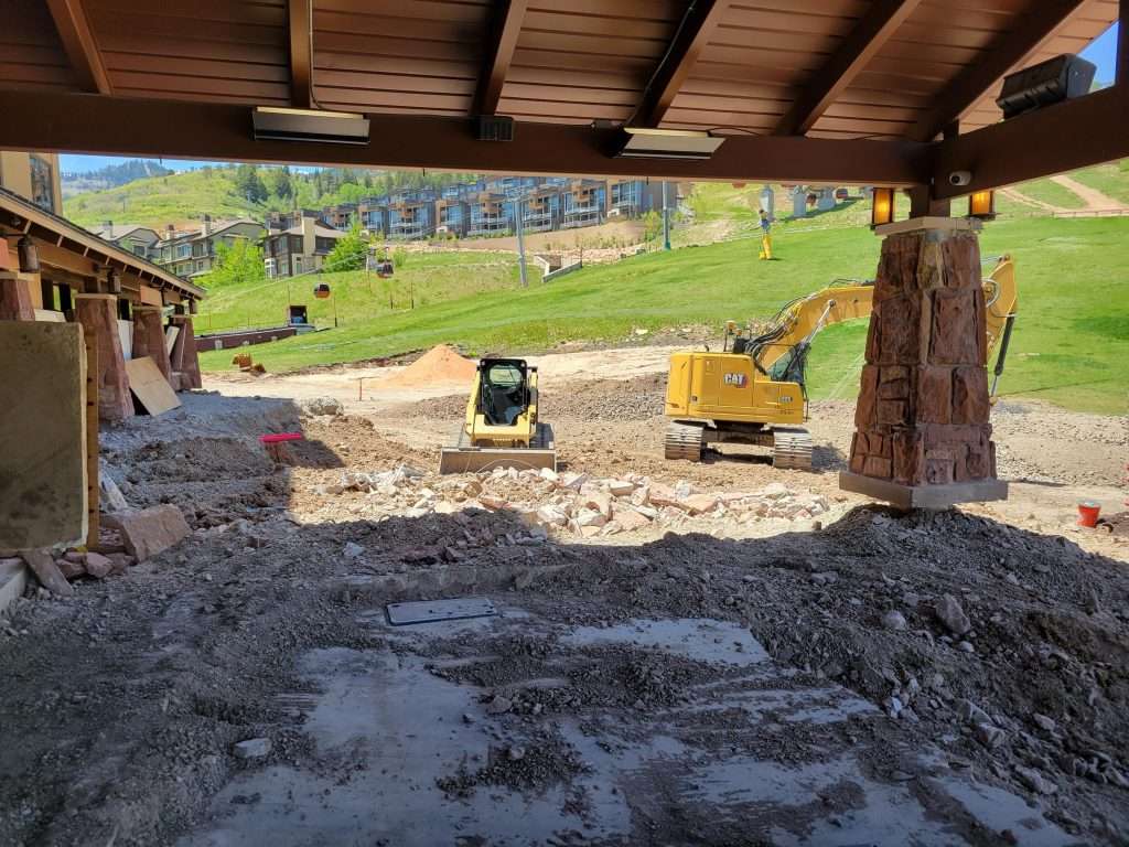 Construction site with heavy machinery under a wooden roof.