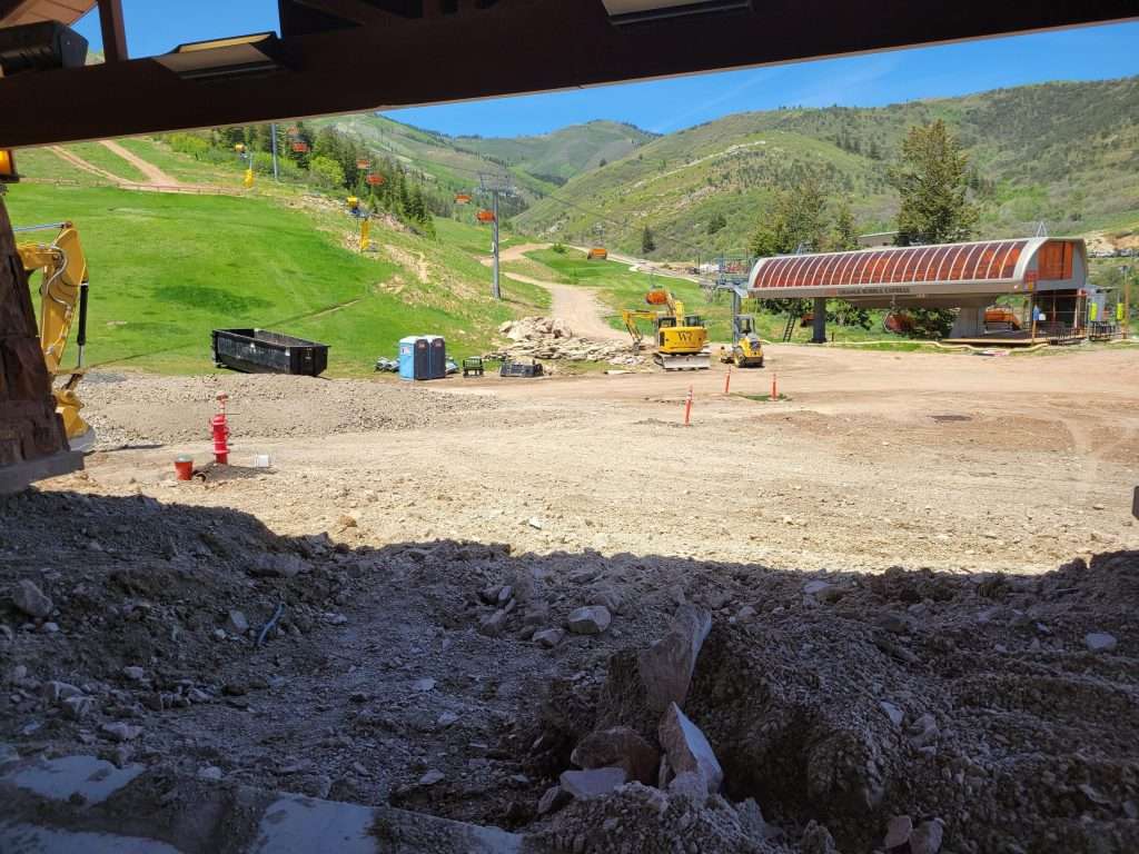 Construction site in a hilly rural area with machinery and workers.