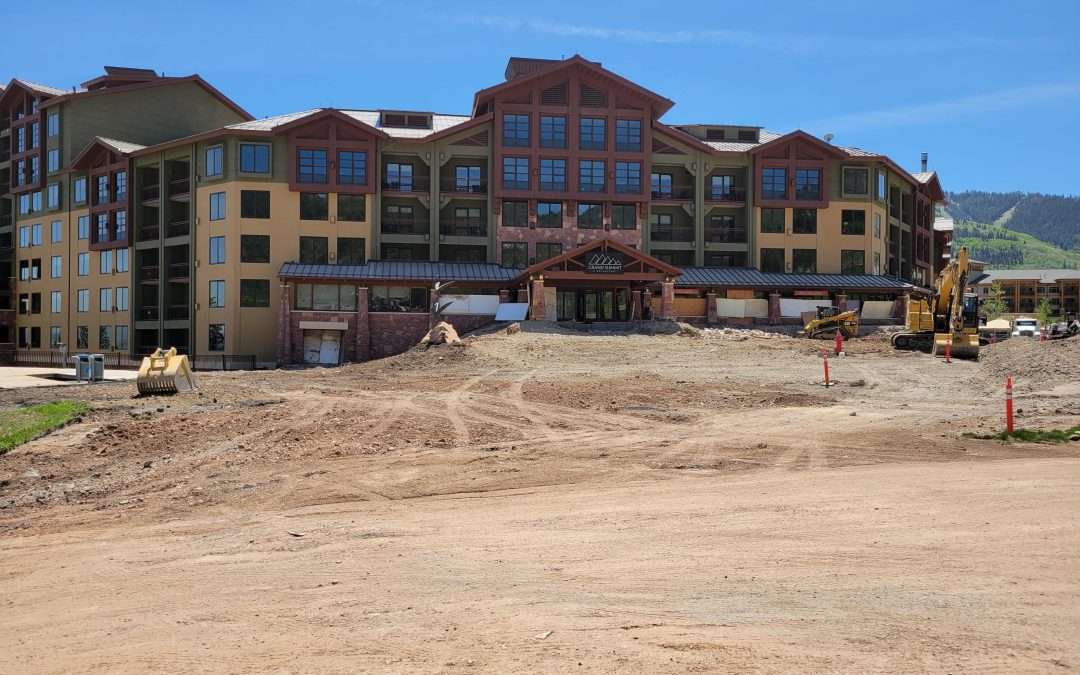 A large building under construction with dirt and construction materials in front.