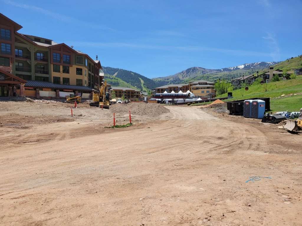 Construction site in a mountainous area with buildings and clear sky.