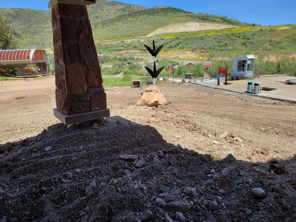 Sculpture base with a dog lying in a sunny, rural area.