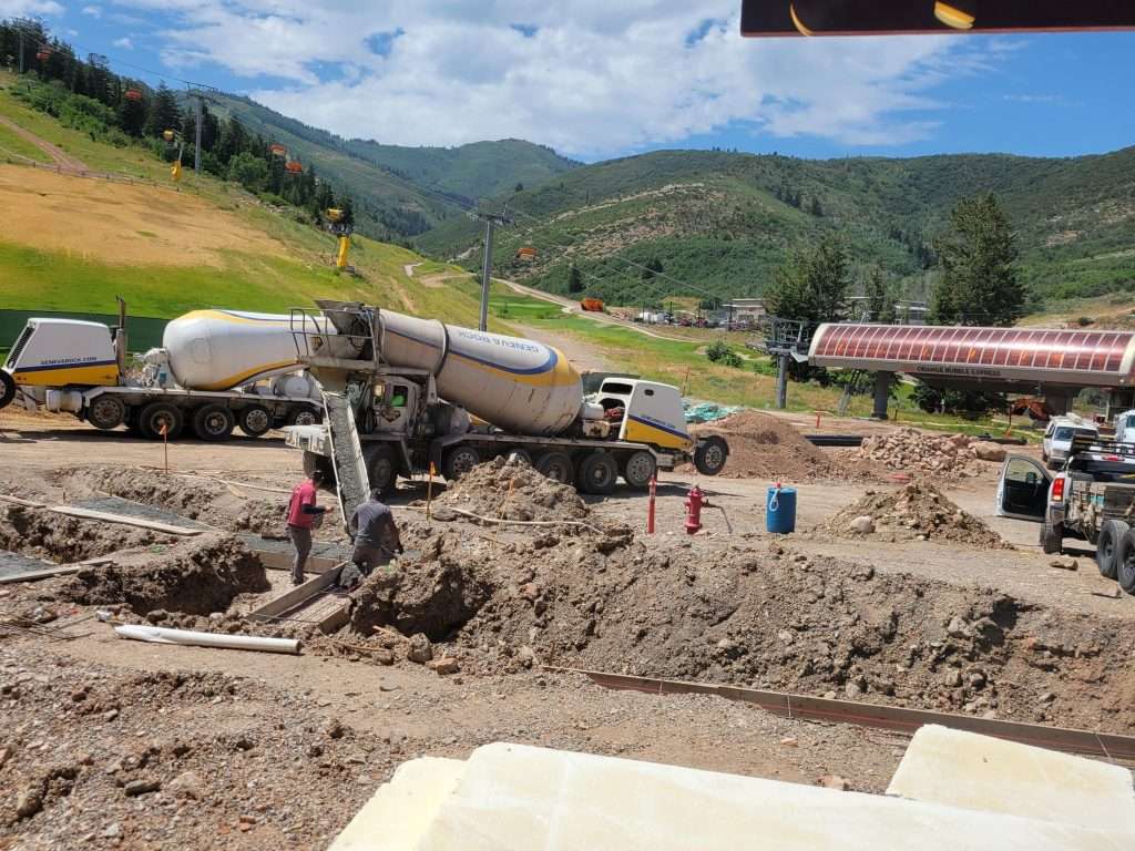 Concrete mixer truck pouring concrete at a construction site in a rural area.