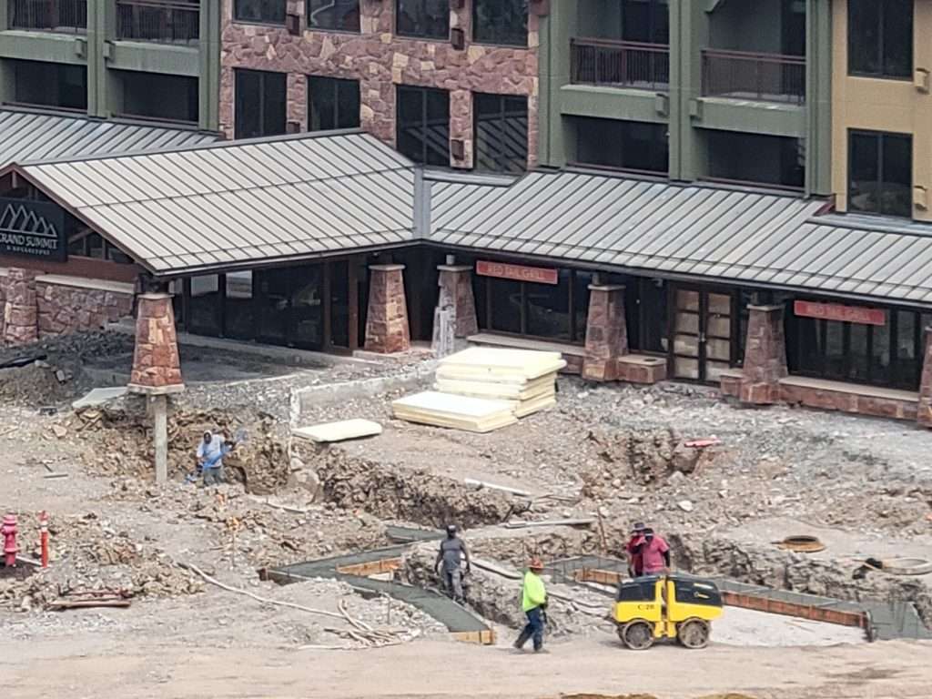 Construction site with workers and heavy machinery near a building.