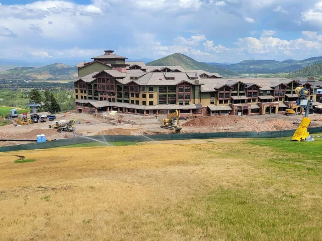 Large building complex near a water body with mountains in the background.