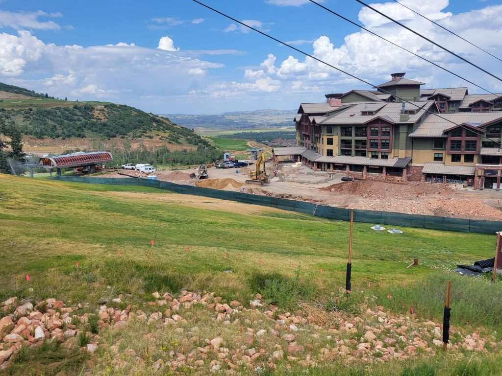 A countryside landscape with a large house under construction and green fields.
