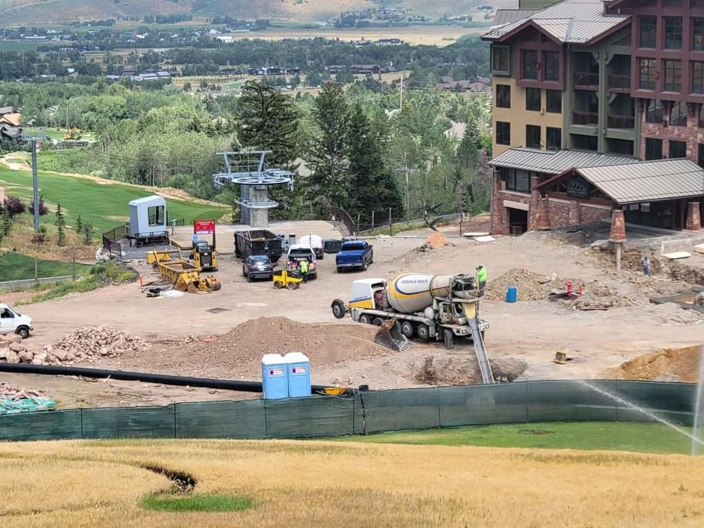 Construction site with equipment near a building and green landscape.