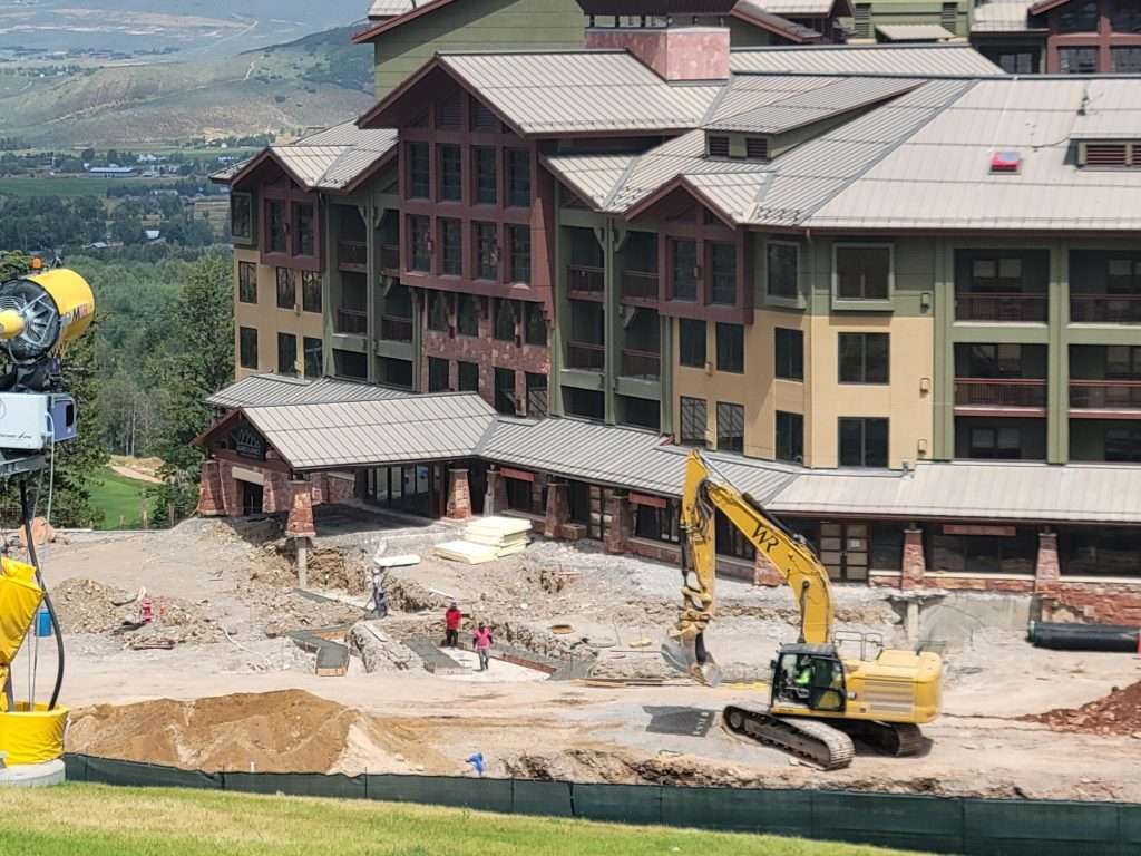 Construction site next to a large building with an excavator at work.