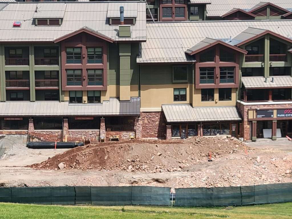 Construction site in front of a multi-story building by a water body.