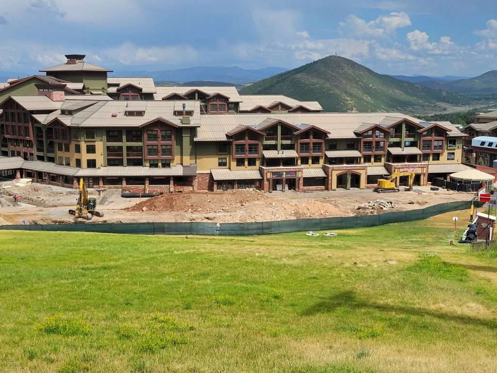 A large resort with multiple buildings near a green lawn and a swimming pool.