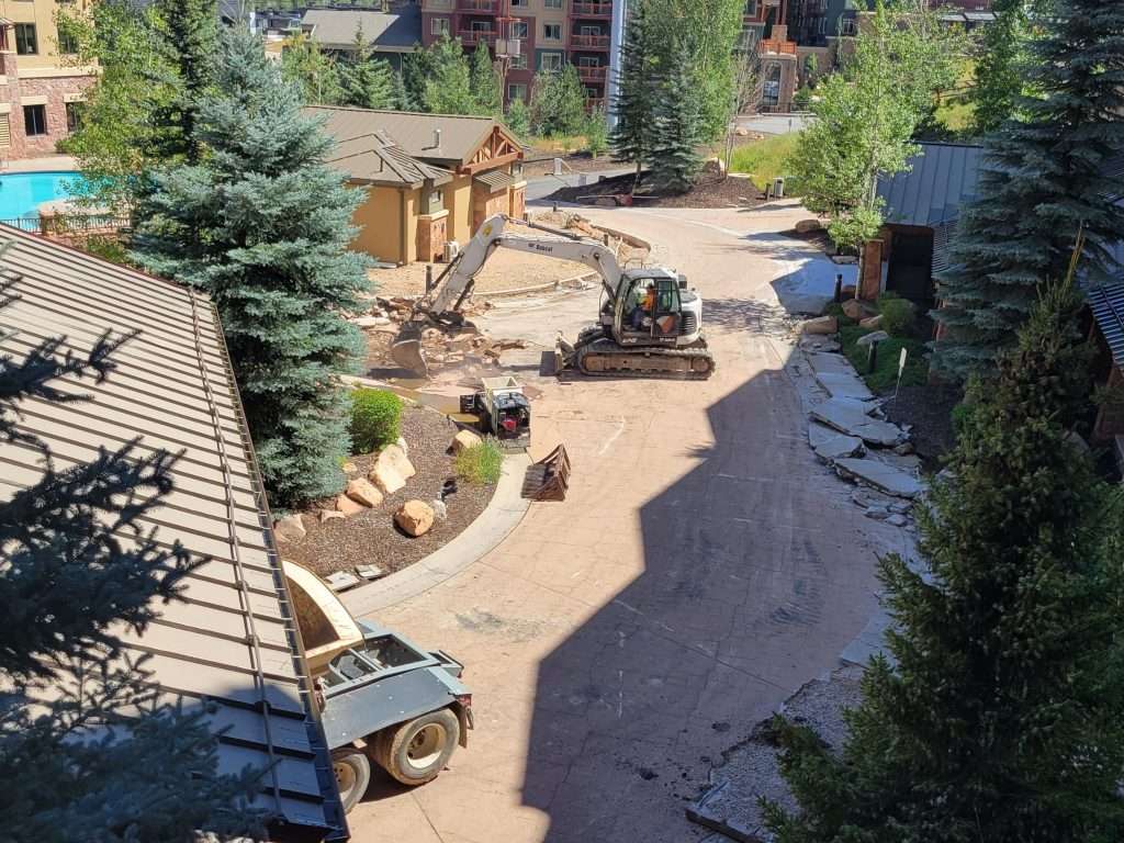 Landscape construction site with heavy machinery and workers.