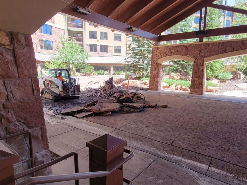 Construction site inside a partially covered building with materials and machinery.