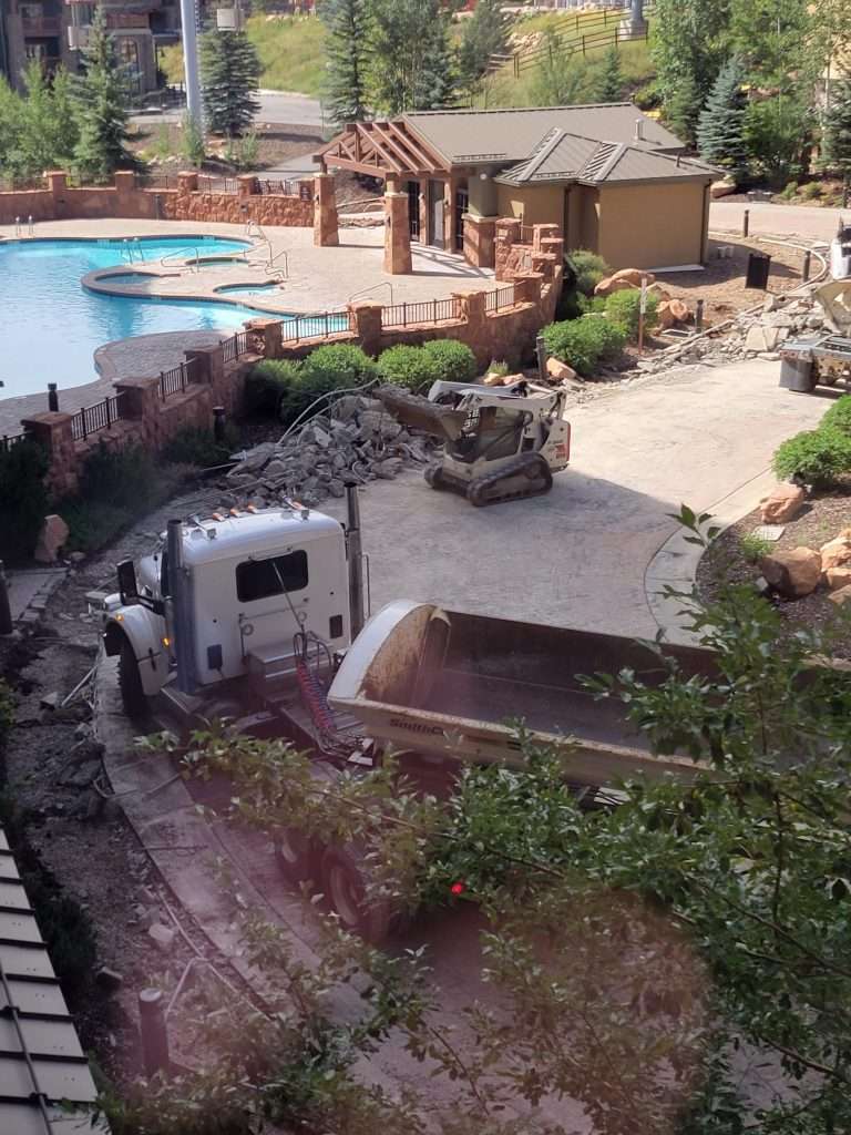 A large truck driving through a residential backyard with a pool.