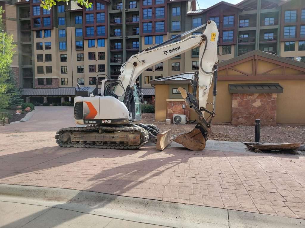 Excavator working on a city construction site near buildings.