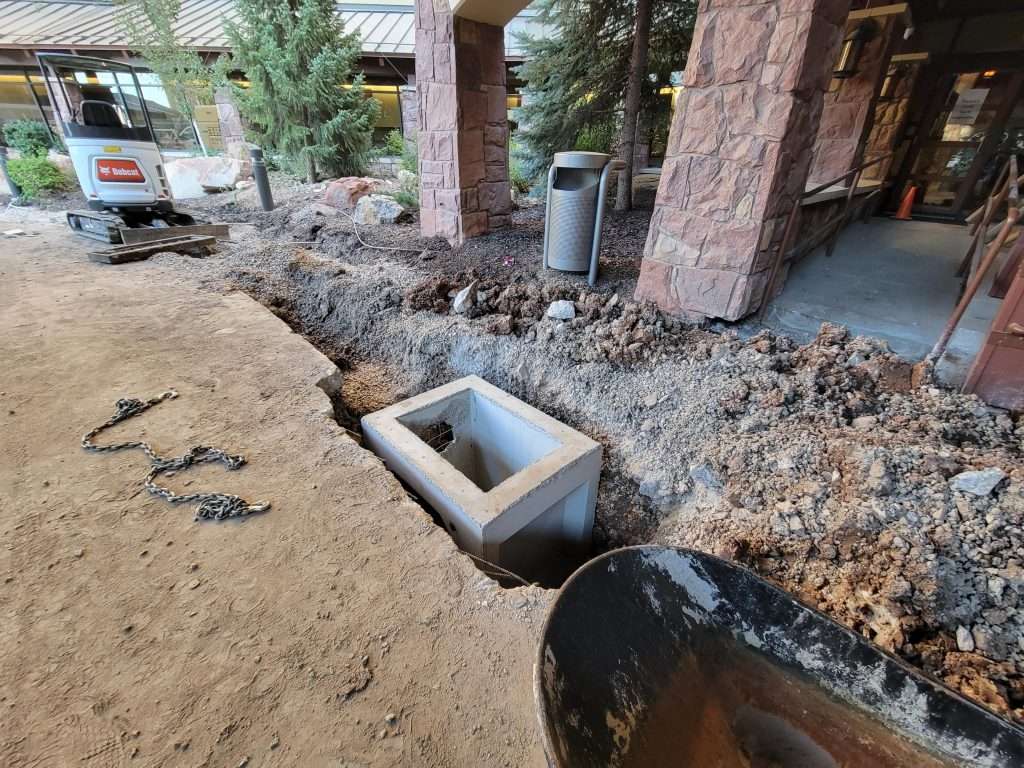 Construction site with drainage installation near a building entrance.