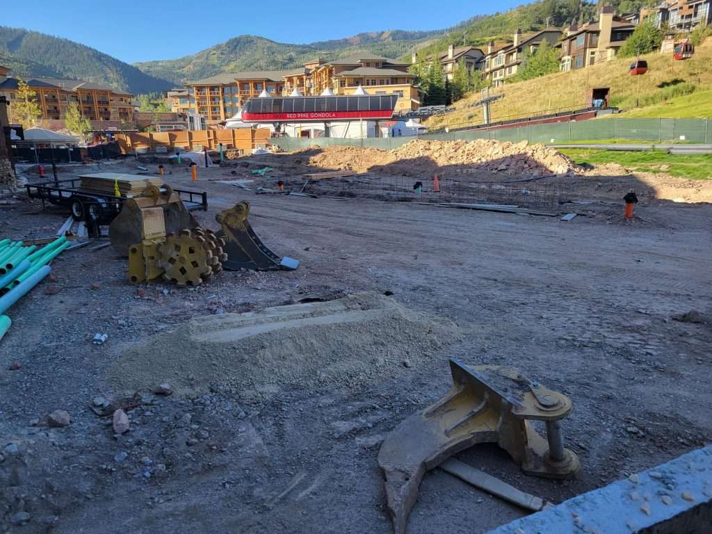 Construction site with dirt piles and equipment under a clear sky.