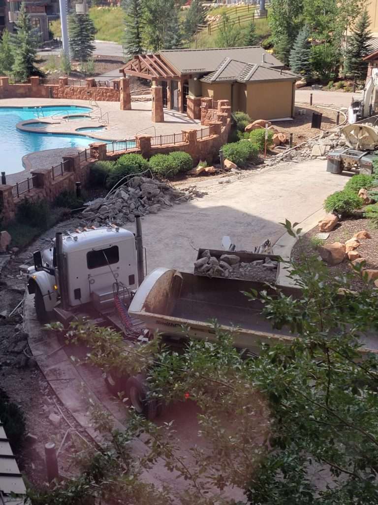 Workers installing a large swimming pool liner outdoors.
