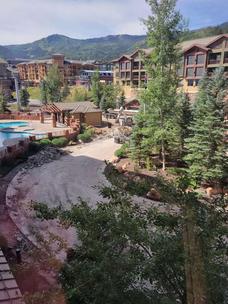 Scenic mountain resort with pools, trees, and wooden lodges.