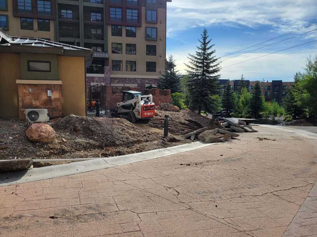Construction site outside a building with machinery and dirt piles.