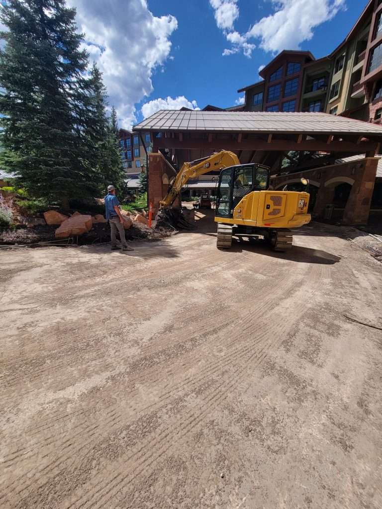 Yellow excavator working at a construction site near a building.