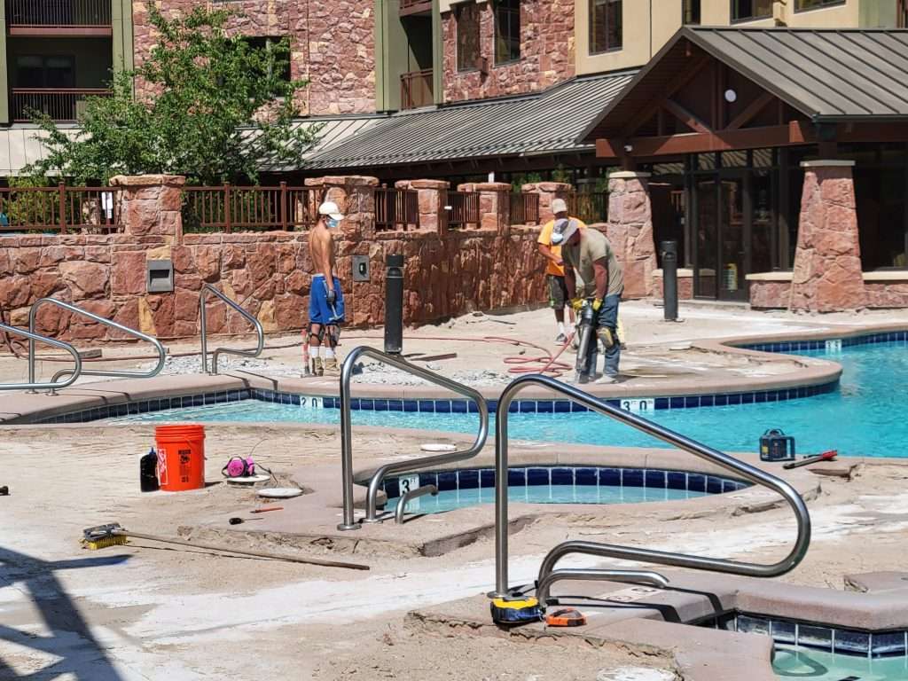 A pool area with cleaning equipment and a person walking nearby.