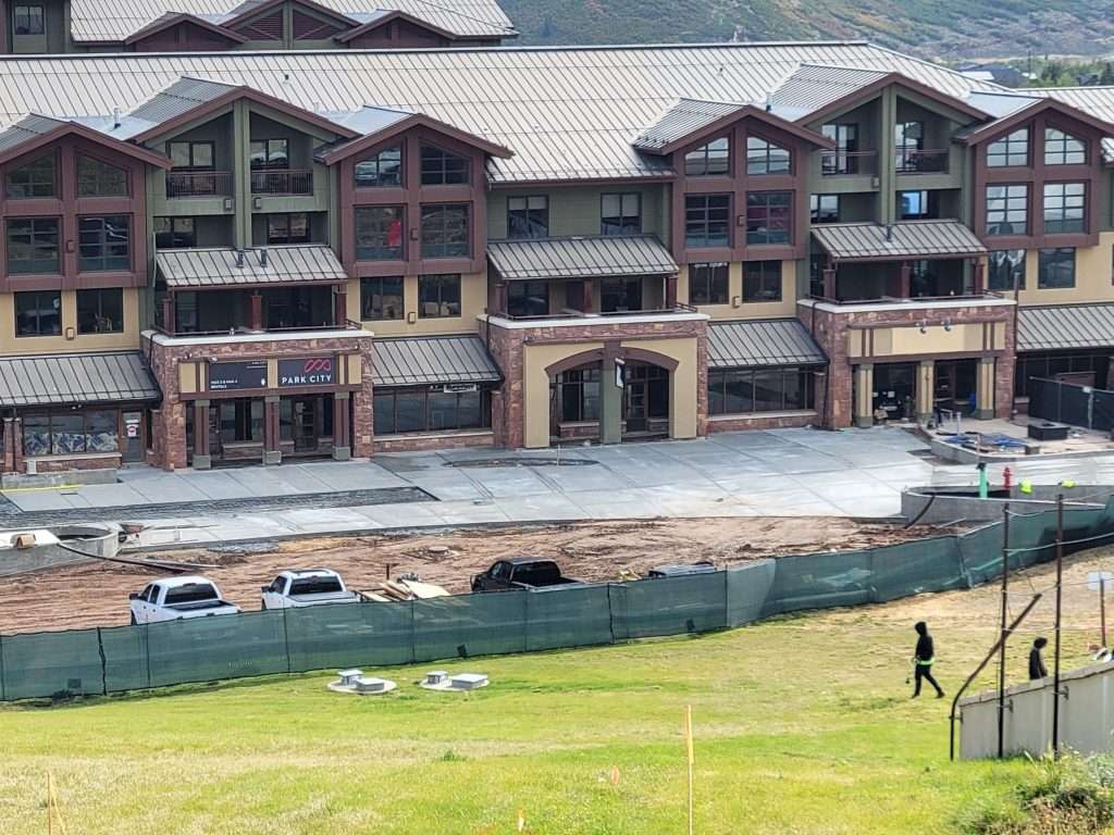 Construction site near a large building with workers on grassy field.