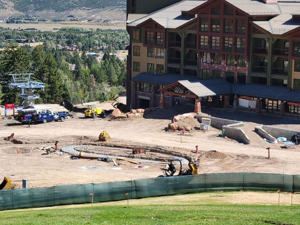 Construction site near a large lodge in a mountainous area.