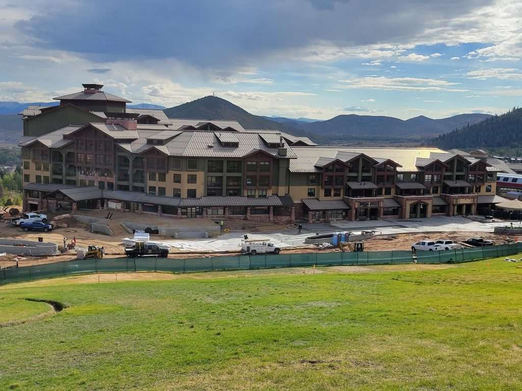 Resort buildings with a scenic mountain backdrop under a cloudy sky.
