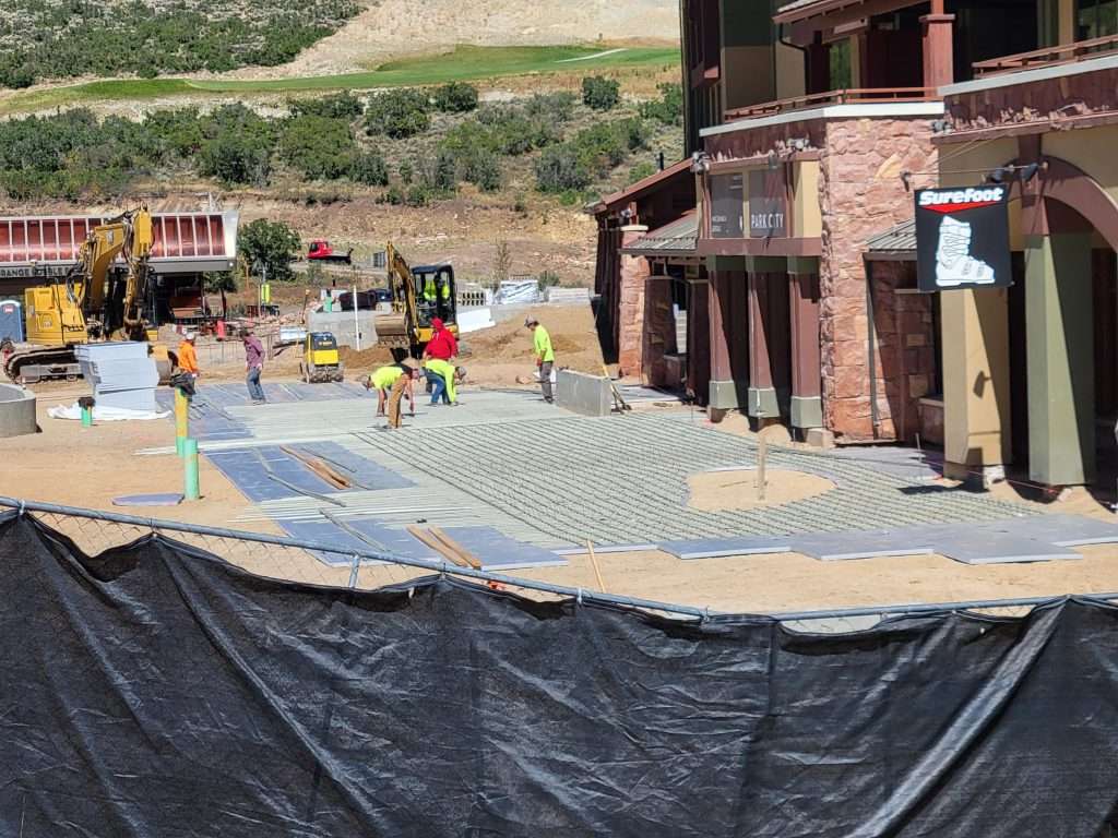 Workers building a stone-paved street in a rustic village setting.