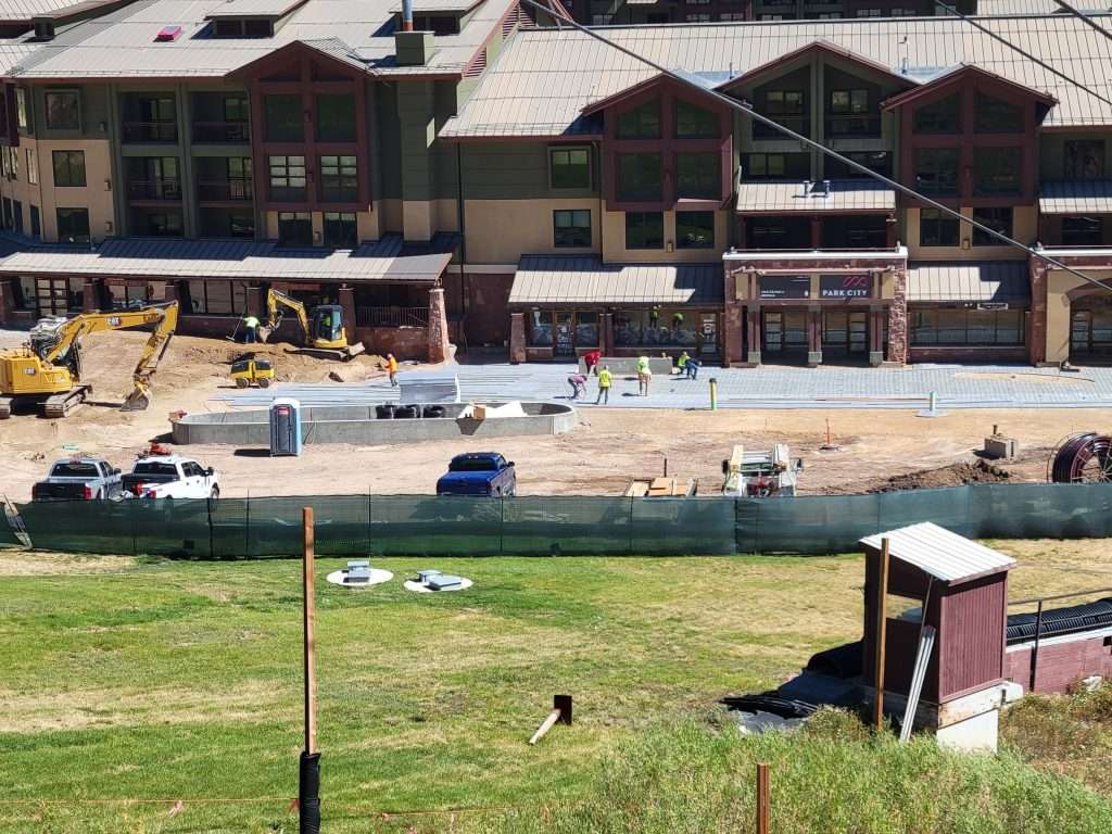 Construction work outside a residential building with vehicles and workers.