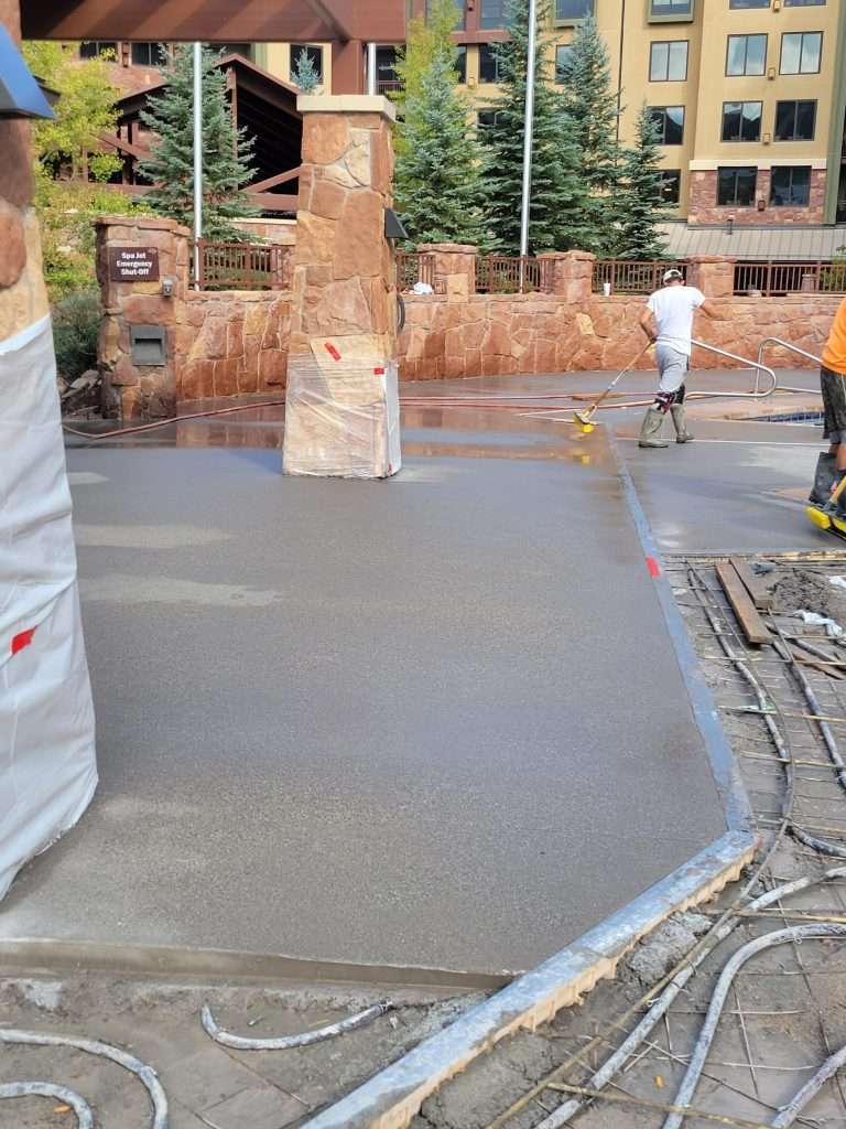 Freshly poured concrete on a driveway near a building entrance.