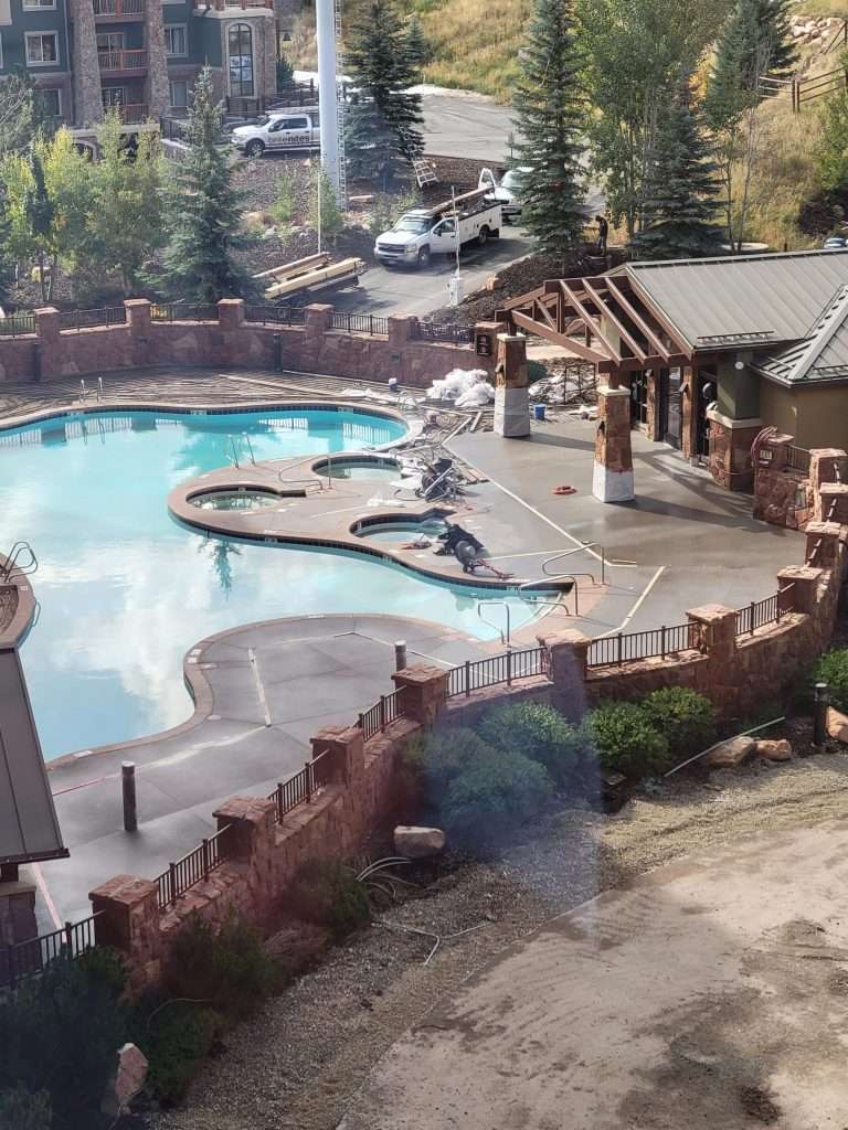 Outdoor pool area with lounge chairs and wooden pergola.