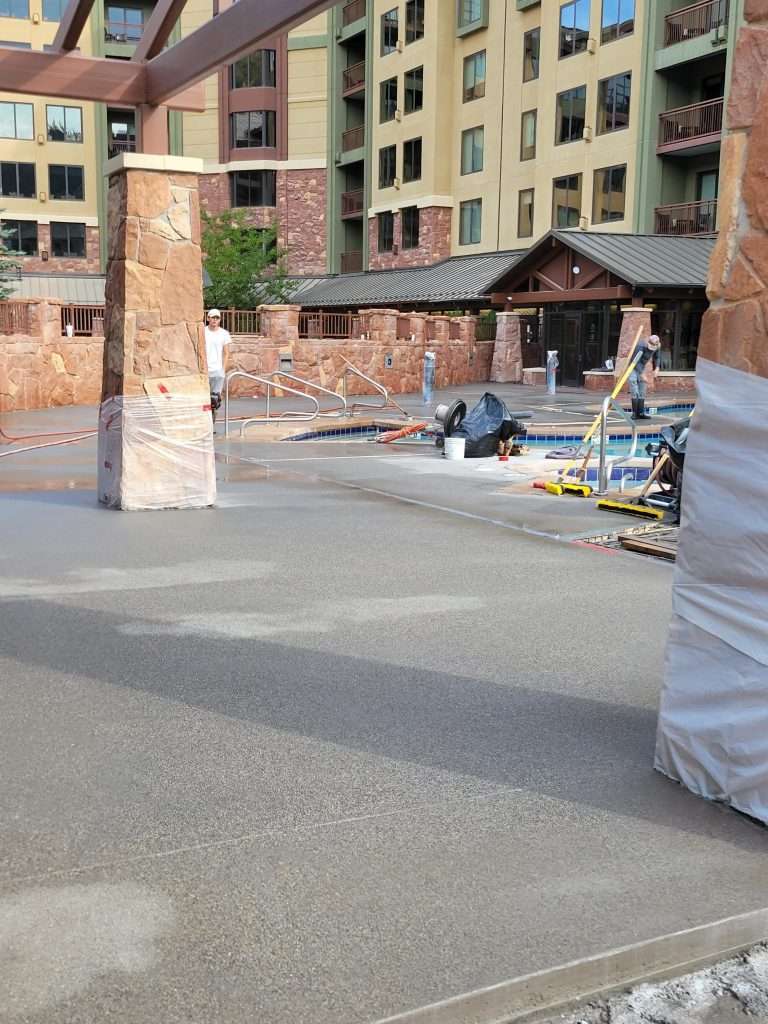 Construction site with building materials and workers near a brick structure.