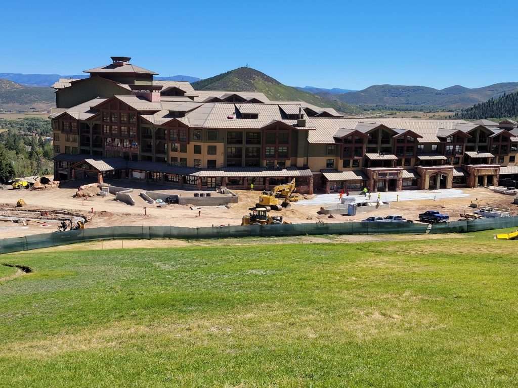 Large rustic lodge with mountain views and green lawn.