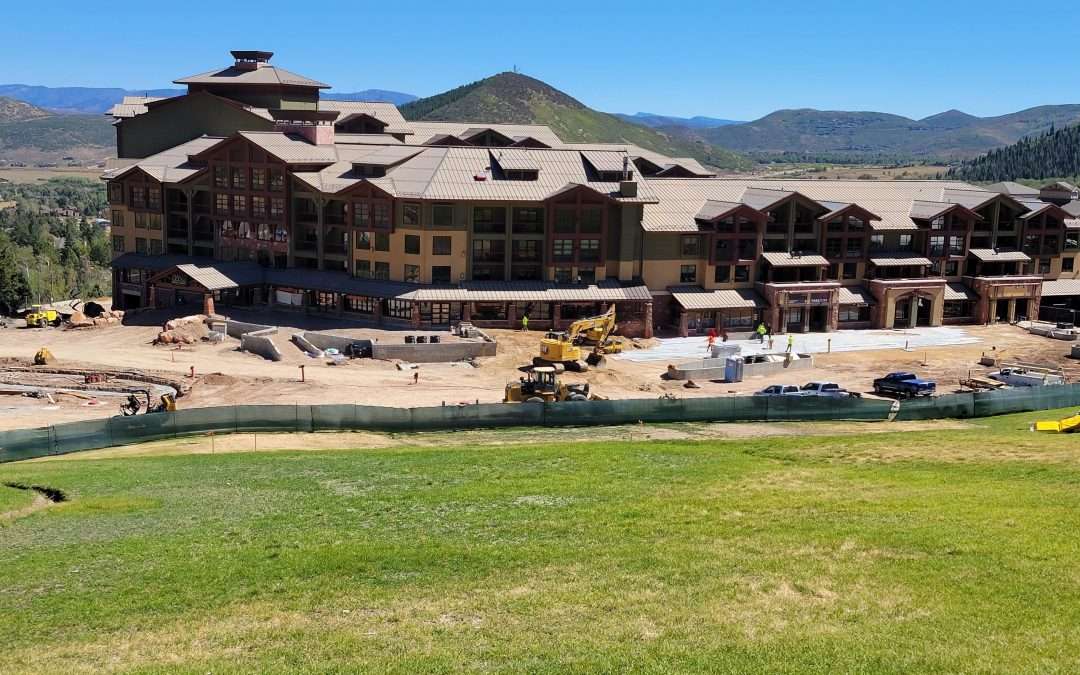 Large rustic lodge with mountain views and green lawn.