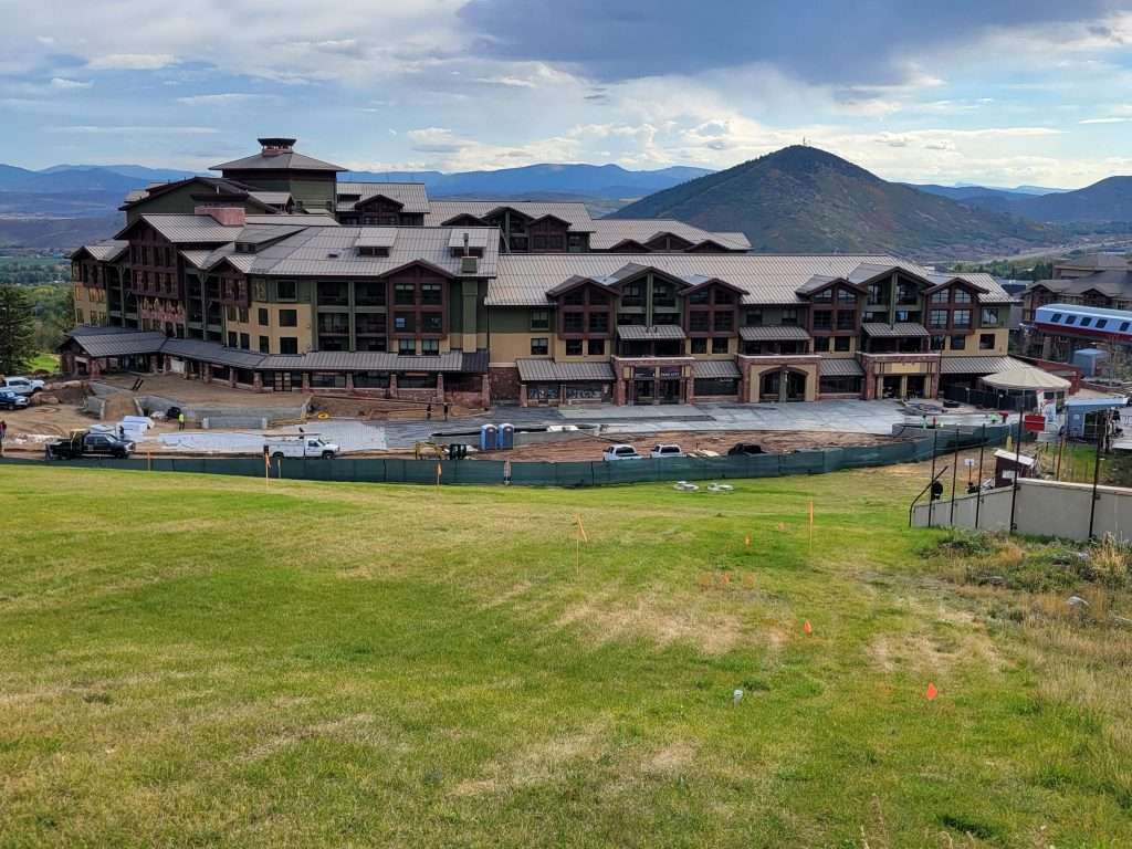 A large resort with pools and mountainous background under a cloudy sky.