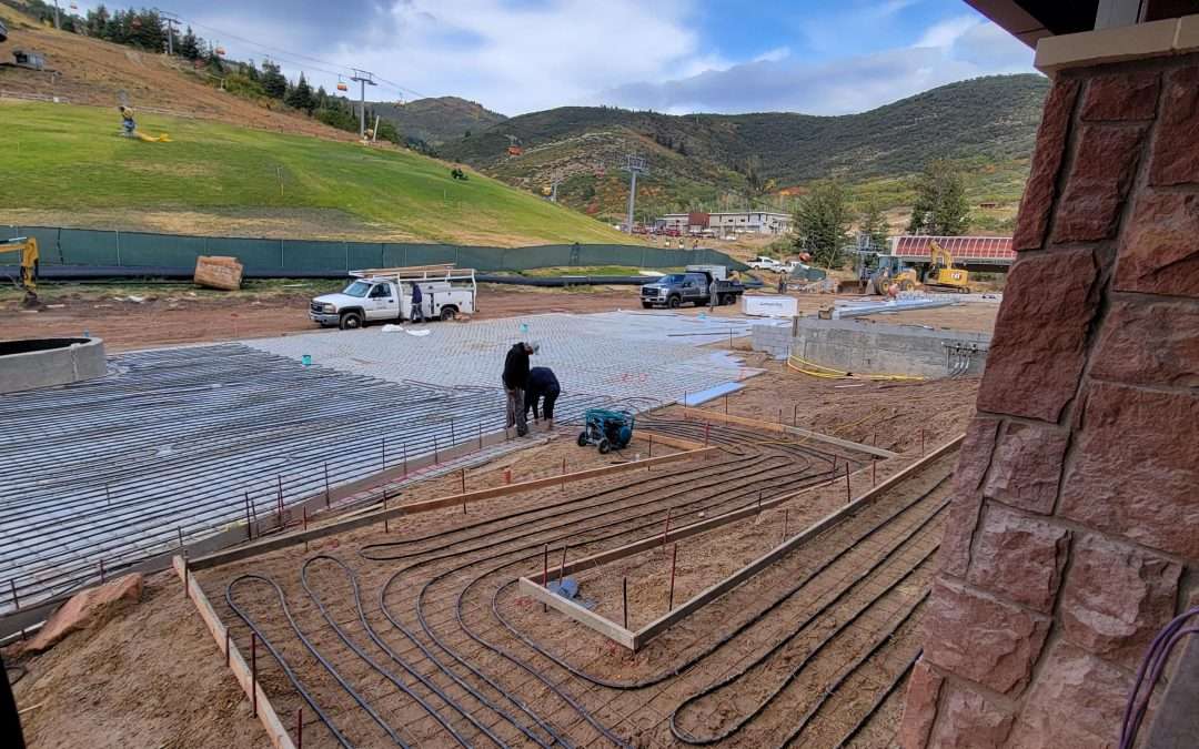 Workers preparing a patio area with coiled irrigation tubing in a scenic mountainous landscape.