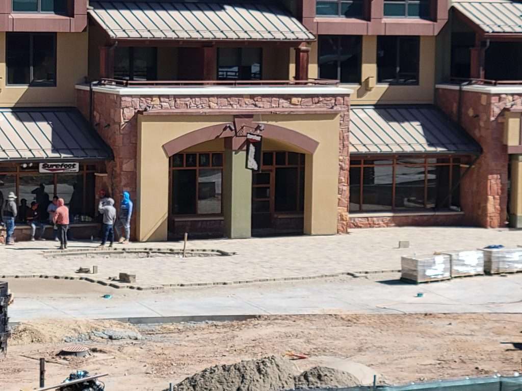 Construction site in front of a commercial building with open doors.