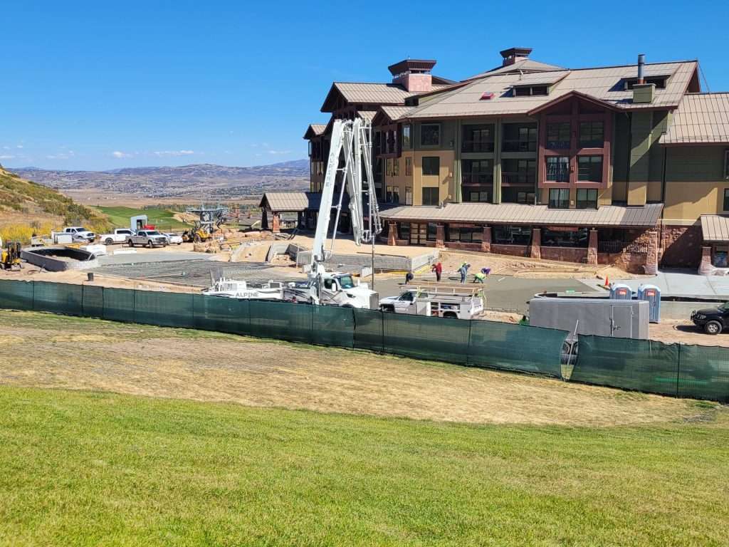 A large wooden house under construction with a green fence around it.