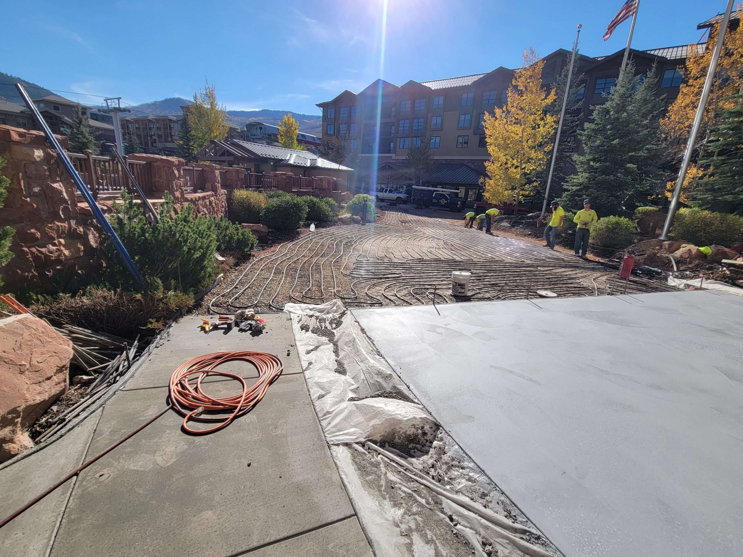 Sunny backyard with garden beds and concrete patio under construction.