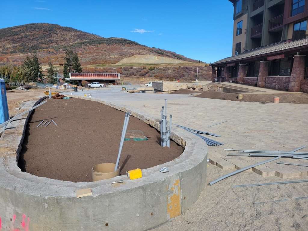 Construction site with a curved concrete foundation near a building.