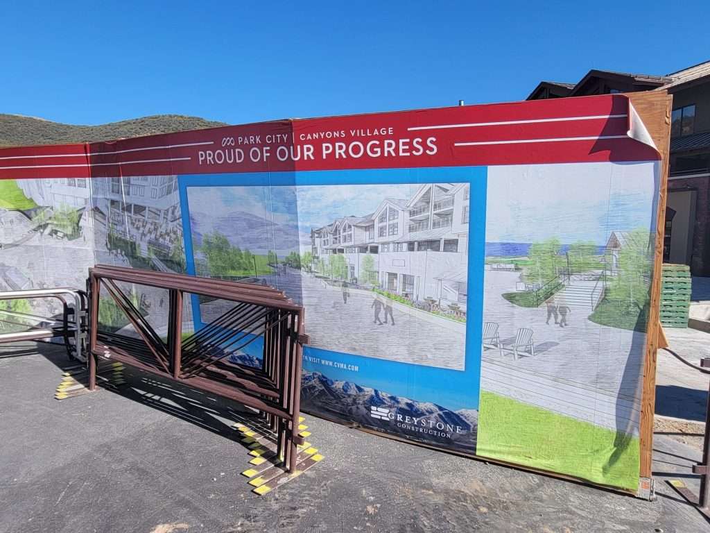Construction site wall with 'Project in Progress' signage and architectural renderings.