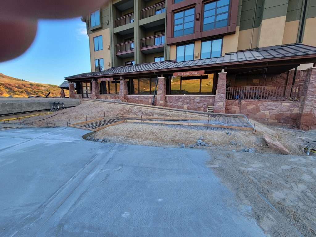 Empty outdoor patio area with wooden beams and large windows.