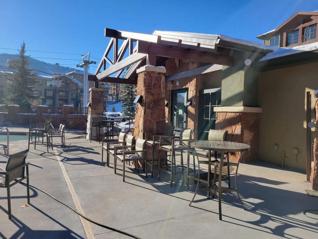 Outdoor seating area with metal tables and chairs under a clear blue sky.